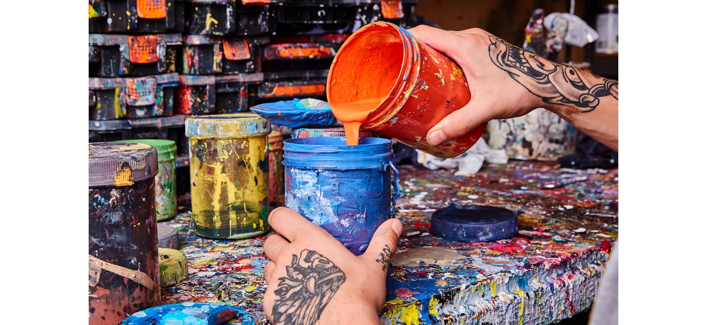A close-up of hands mixing blue and orange paint colours in the Apparition Media studio.